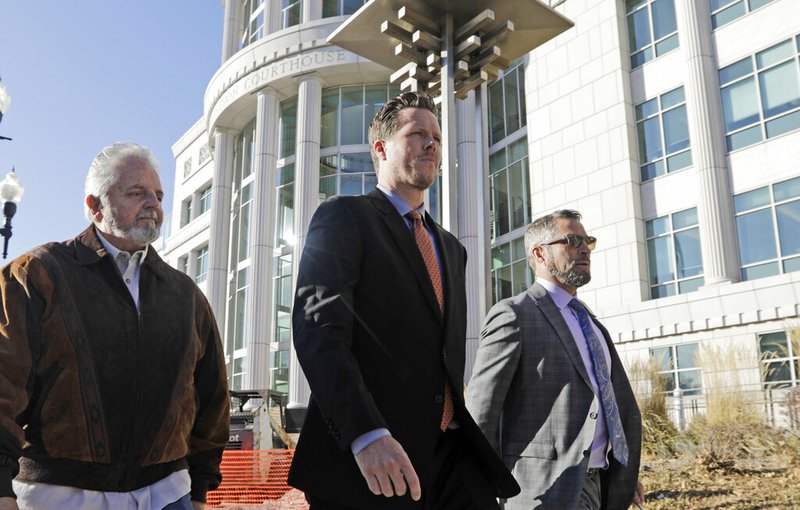 Paul Petersen, center, an Arizona elected official accused of running a multi-state adoption scheme, leaves court following an initial appearance on charges filed in the state Friday, Nov. 15, 2019, in Salt Lake City.  (AP Photo/Rick Bowmer)