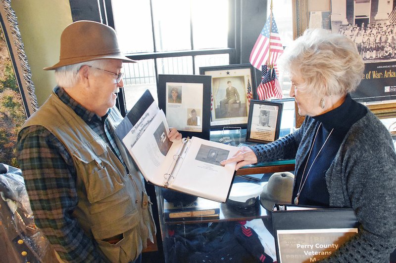 Mike Allison, president of the Perry County Historical Museum, and Beverly Doremus, board secretary, view photographs of Perry County veterans that are displayed in scrapbooks at the museum in Perryville. The museum is normally open from 10 a.m. to 2 p.m. every fourth Saturday of the month and will be open additional days in December, when the museum will host the exhibit Territorial Arkansas: The Wild Western Frontier, on loan from the Arkansas State Archives.