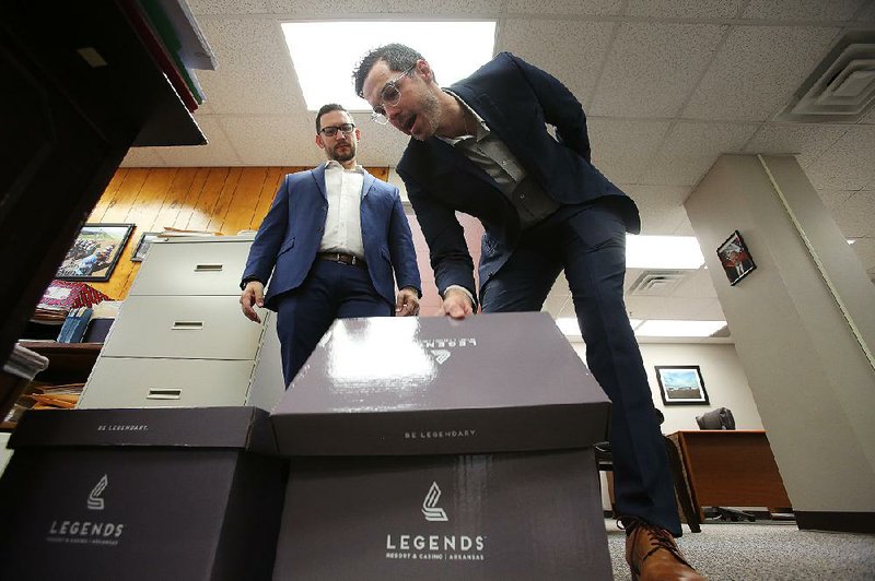 Cherokee Nation Businesses representatives Matt Perrier (left) and Ben Elder deposit the group’s amended Pope County casino application Friday at the Arkansas Racing Commission office in Little Rock. 