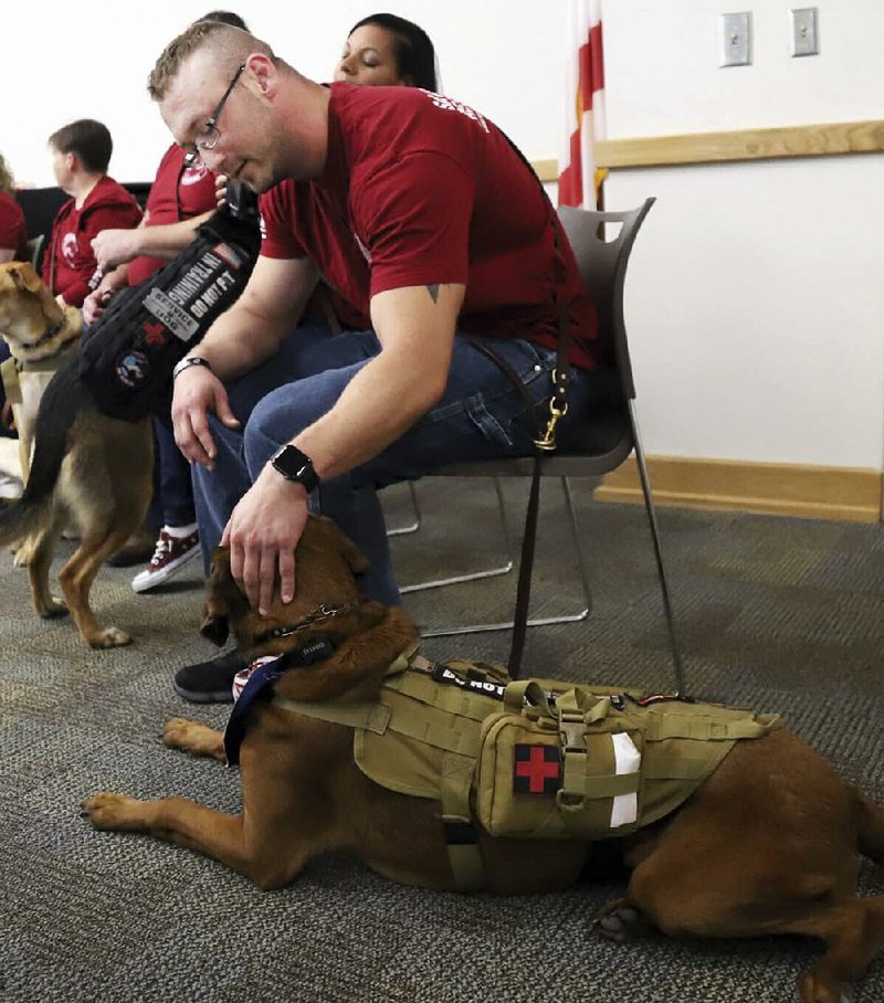 Retired Marine Rob Reed pets his service dog, Kimball, during Healing Paws for Warriors graduation ceremony for veterans/ canine service teams Friday in Niceville, Fla. 