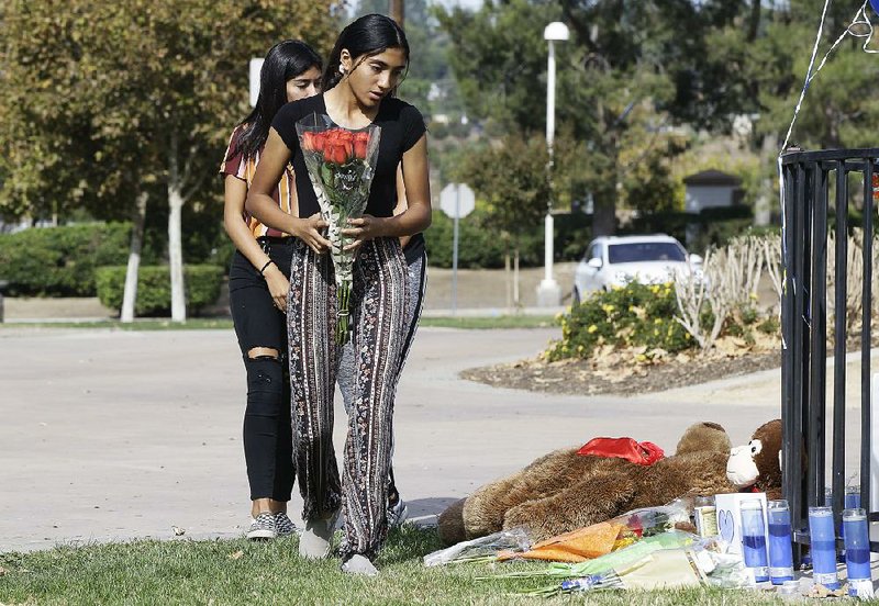 Saugus High School students Liliana, 15, (right) and her sister Alexandra, 16, carry a bouquet of roses Friday to place at a memorial for victims of Thursday’s shooting at the school in Santa Clarita, Calif. More photos are available at arkansasonline.com/1116shooting/ 