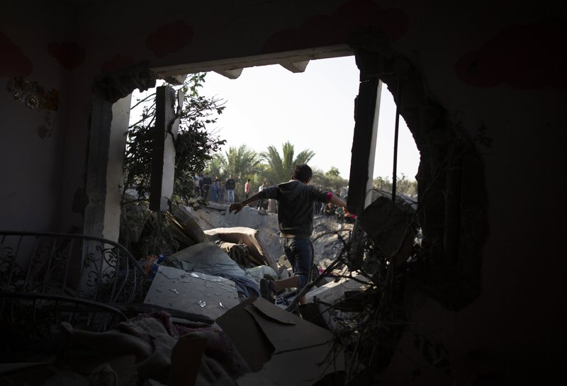 A Palestinian boy walks through a hole in a wall of a destroyed house following overnight Israeli missile strikes, in the town of Khan Younis, southern Gaza Strip, Thursday, Nov. 14, 2019. (AP Photo/Khalil Hamra)