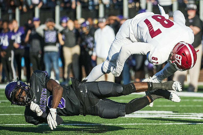 Henderson State tight end Ayden Shurley (right) is tripped up by Ouachita Baptist defensive back Keandre Evans during OBU’s victory  in the 93rd Battle of the Ravine on Saturday in Arkadelphia. See more photos at arkansasonline.com/1117bravine.