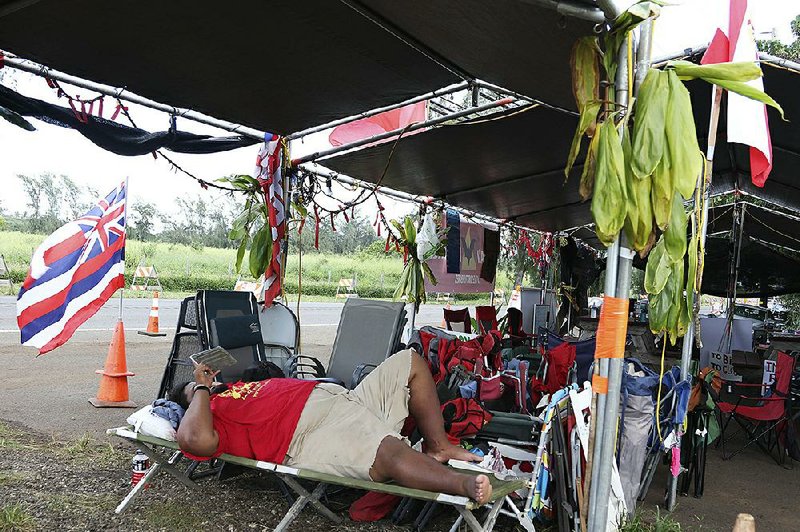 Caleb Nawahine rests on a cot last month at an encampment for protesters who are opposing the construction of wind turbines in Kahuku, Hawaii. 