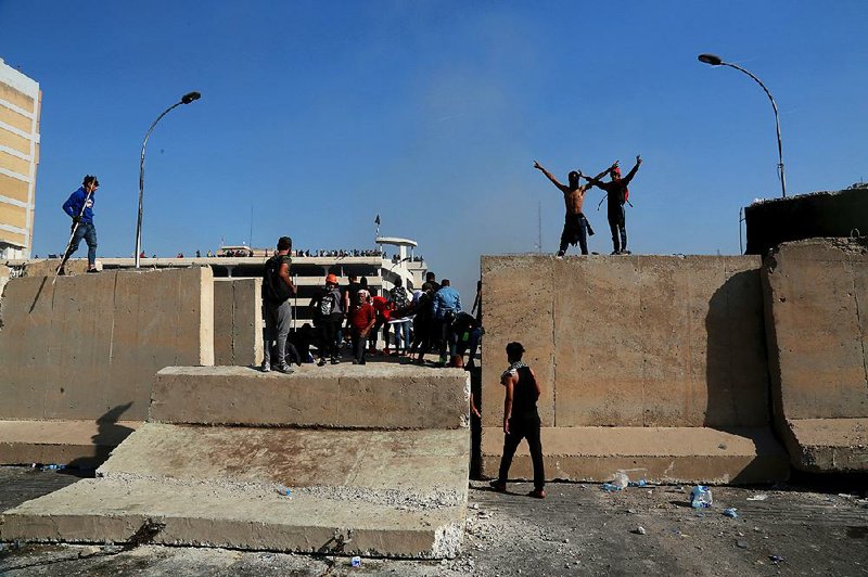 Iraqi protesters on Saturday topple concrete walls erected by security forces to close the Sinak Bridge that leads to the Green Zone in Baghdad. 