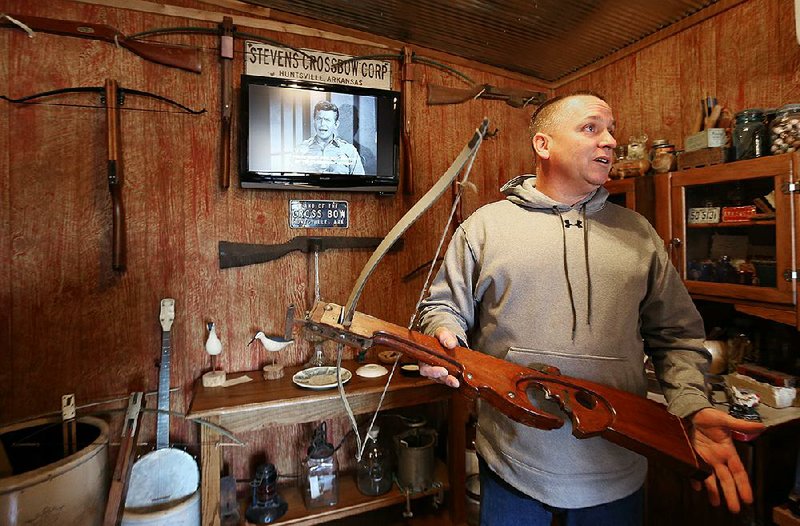 Jason Yates, the owner of Sparky’s Garage, describes Wednesday one of the Huntsville-made crossbows that’s on display in the garage’s waiting room. 