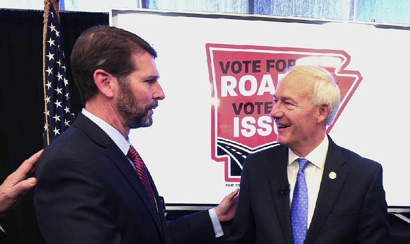 Transportation Department chief Scott Bennett (left) and Gov. Asa Hutchinson finish a news conference Friday at the Poultry Federation office in Little Rock that kicked off a campaign for a ballot amendment to raise money for state roads. 