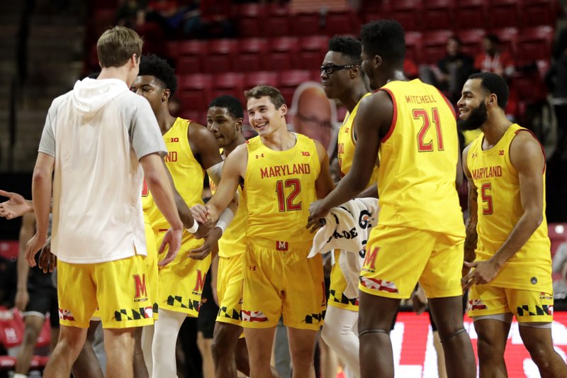 Maryland players swarm guard Reese Mona (12) after he scored his second 3-point shot against the Oakland during the second half of Saturday's game in College Park, Md. Maryland won 80-50. - Photo by Julio Cortez of The Associated Press
