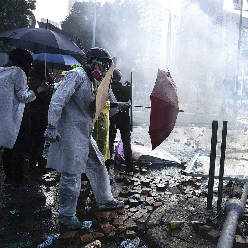 Protesters seek cover Sunday during a confrontation with police at Hong Kong Polytechnic University. More photos at arkansasonline.com/1118hongkong/. 