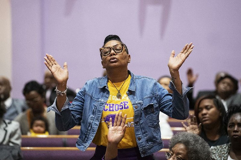 Tracey Cooper, wearing a Camden High School football T-shirt, prays Sunday during a Mass at a church in Camden, N.J., after a shooting at a Friday night football game in the city critically injured a child. Six men have been charged in the shooting. 