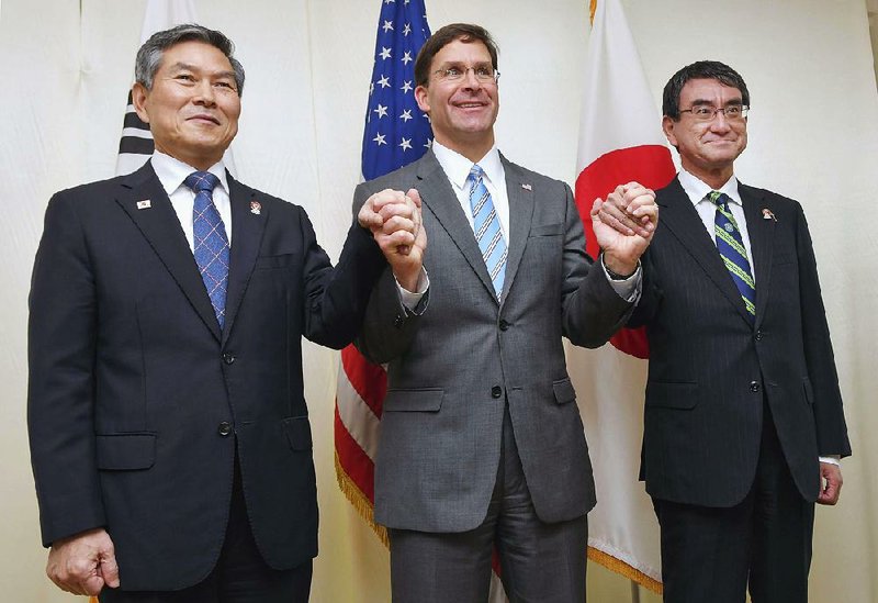 South Korean Defense Minister Jeong Kyeong Doo (from left), U.S. Defense Secretary Mark Esper and Japanese Defense Minister Taro Koon join hands Sunday before entering talks in Bangkok. 