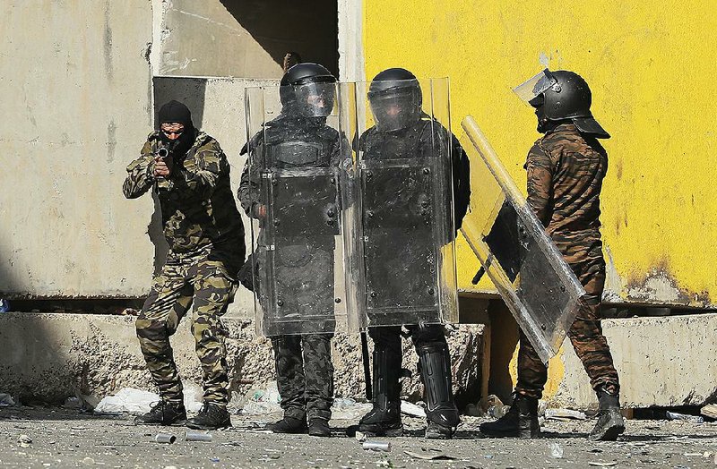 Riot police stand ready Sunday to disperse anti-government protesters during clashes in Baghdad. 