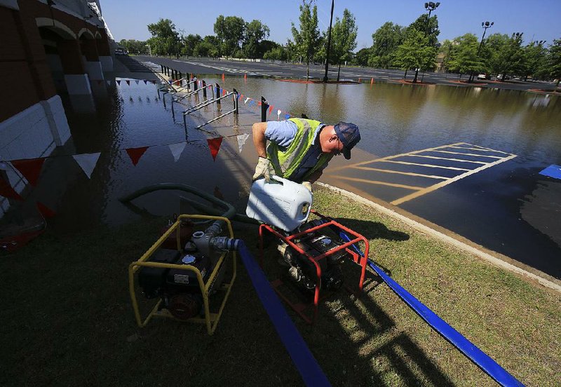 North Little Rock Street Department employee Charlie Harris primes a pump on June 1 to pump Arkansas River floodwaters out of the parking lot at Dickey-Stephens Park. 
