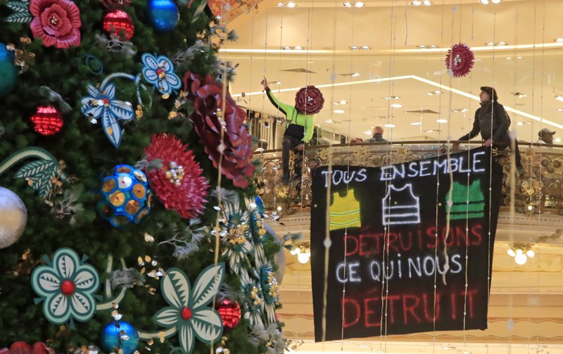 Yellow vest demonstrators shout after they unfurl a giant banner that reads, 'all together, let us destroy what is destroying us' as they stage a protest at the Galeries Lafayette shopping mall in Paris, Sunday, Nov. 17, 2019. Yellow vest protesters staged new actions Sunday across France to mark the birth last year of their movement for economic justice, one day after scuffles between Paris police and activists marred the anniversary. (AP Photo/Michel Euler)