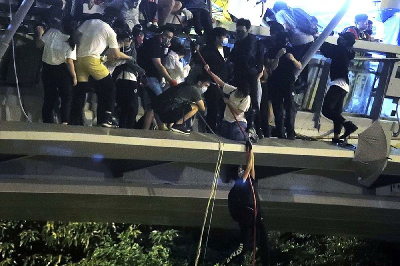 Protesters use ropes to lower themselves from a pedestrian bridge Monday as they try to escape from police at Hong Kong Polytechnic University. More photos are available at arkansasonline.com/1119hongkong/ 