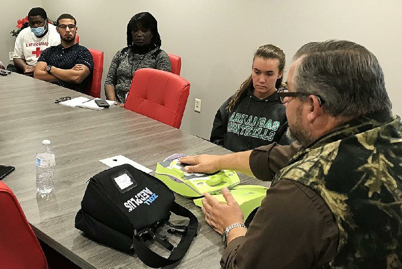 John Badgley (right), operations director for Emergency Ambulance Service Inc., instructs Pine Bluff Aquatic Center lifeguards and staff members Monday in the use of the facility’s new automated external defibrillator. 