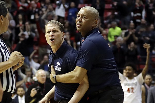 Nevada head coach Eric Musselman, center, is held back by assistant coach Johnny Jones, right, as he yells at game official Tommy Nunez, center left, after an NCAA college basketball game against San Diego State Saturday, March 3, 2018, in San Diego. San Diego State won, 79-74. (AP Photo/Gregory Bull)

