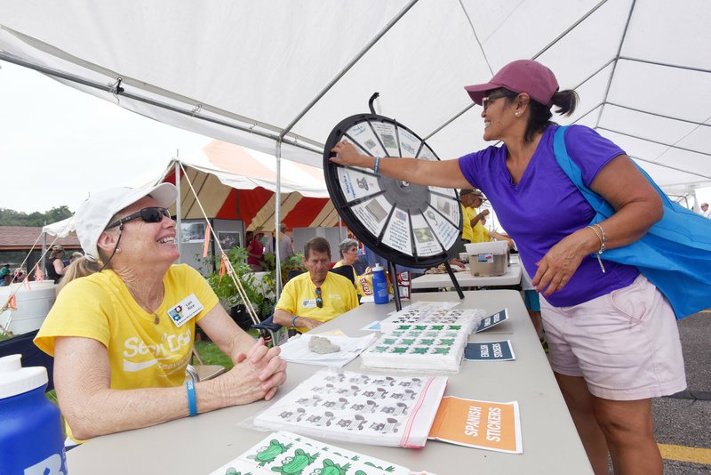 Lori Rice (left), a Northwest Arkansas Master Naturalist, watches Martha Rodriguez of Springdale spin a wheel on Saturday Aug. 17 2019 to win a prize at the 14th annual Secchi Day Science Fair at Beaver Lake.