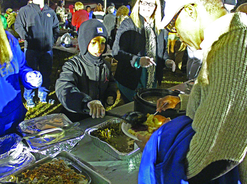 Come One, Come All: One young volunteer serves diners at the 2018 community Thanksgiving dinner. This year’s community Thanksgiving meal will be held in the parking lot of One Community Church, 701 S. West Ave., tomorrow evening starting at 6 p.m. The dinner is free to attend and open to all.