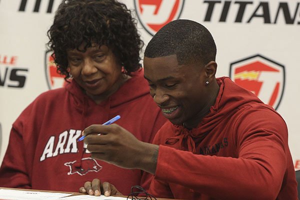 Davonte Davis signs to play basketball at the University of Arkansas while his grandmother Yvette Davis watches during a ceremony Tuesday, Nov. 19, 2019, in Jacksonville. 