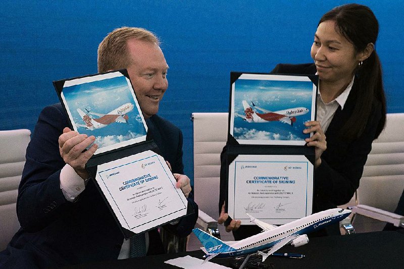 Stan Deal (left), president of Boeing’s commercial airplanes division, and Air Astana Chief Planning Officer Alma Aliguzhinova display documents Tuesday  to commemorate  the Kazakhstan carrier’s purchase of Boeing Max planes at the Dubai Airshow in the United Arab Emirates. 