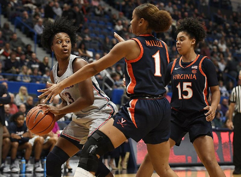 Connecticut’s Christyn Williams (left) looks to pass as Virginia’s  Carole Miller (1) and Kylie Kornegay-Lucas defend in the Huskies’  83-44 victory over Virginia on Tuesday night in Hartford, Conn. Williams (Central Arkansas Christian) scored 17 points as the Huskies extended their home winning streak to 96 games. 