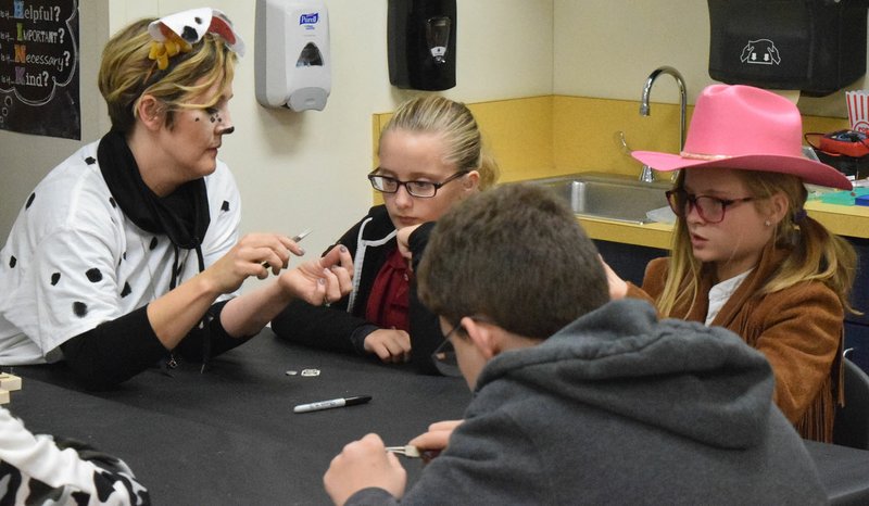 Westside Eagle Observer/MIKE ECKELS Rachel Gibson (left) helps Abigail Zellars, Kylie Lowery and Emilio Smith-Gomez (foreground) with their closed-circuit project during the SPARK/Amazeum after school program Oct. 31 at Northside Elementary in Decatur.