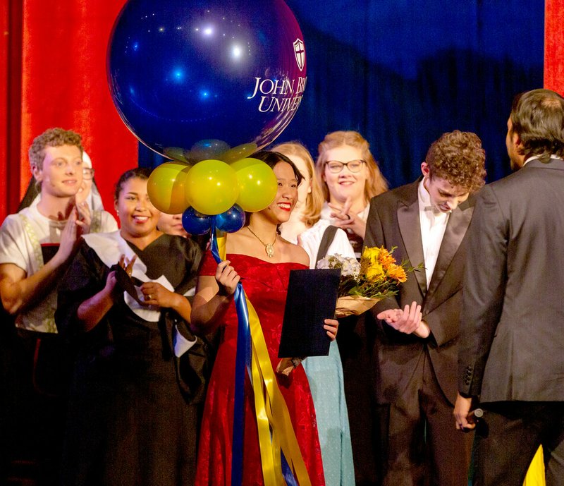 Katie Mercer/Special to the Herald-Leader Marcos Gutierrez, admissions counselor at John Brown University, suprised Siloam Springs High School senior Lena Lor with a full-tuition scholarship to JBU after the school musical on Friday evening. The $110,000 scholarship, awarded over four years, was awarded to two students this year.