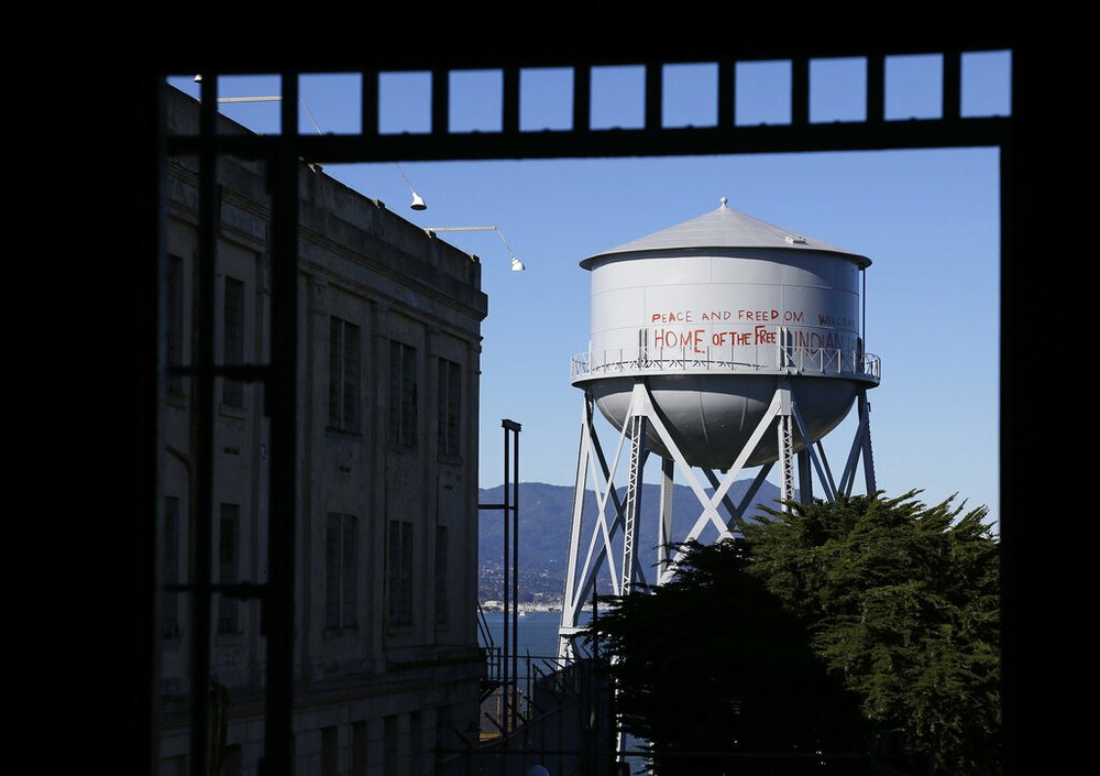 This Jan. 14, 2013, file photo, shows a restored water tower with words that read "Peace and Freedom Welcome Home of the Free Indian Land" seen through an entryway to the main cell house on Alcatraz Island in San Francisco. The words were first written on the water tower during the Native American occupation. The week of Nov. 18, 2019, marks 50 years since the beginning of a months-long Native American occupation at Alcatraz Island in the San Francisco Bay. (AP Photo/Eric Risberg, File)