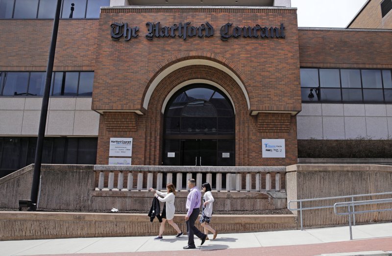 In this April 25, 2016 file photo, workers walk past the front entrance of the Hartford Courant building in Hartford, Conn. Hedge fund Alden Global Capital is now the largest shareholder of Tribune Publishing, the company that owns the Hartford Courant, the Chicago Tribune, Baltimore Sun and New York Daily News. Tribune says Alden, a hedge fund known for layoffs and slashing costs at newspapers it acquires, purchased the 25% stake from former Tribune chairman Michael Ferro. (AP Photo/Charles Krupa, File)