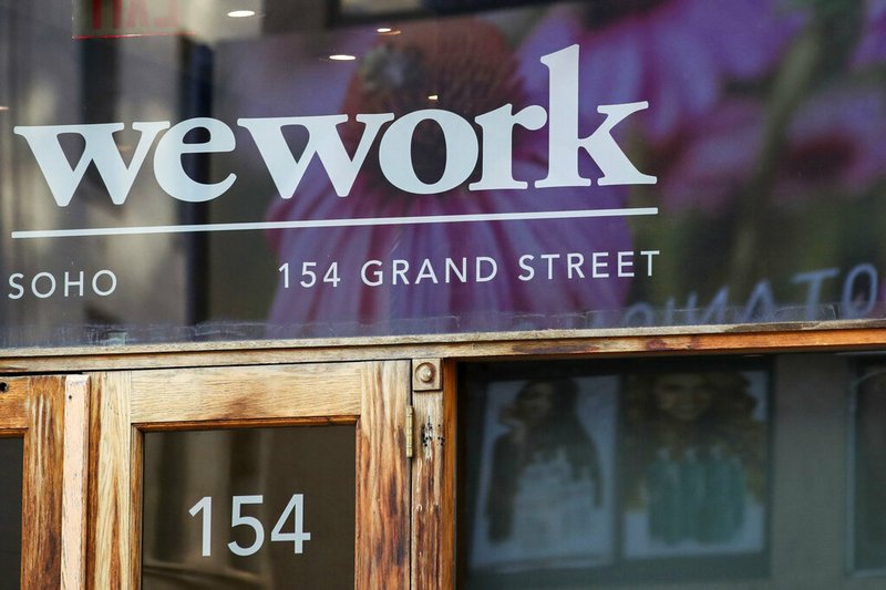 This Oct. 15, 2019, file photo shows a WeWork logo at the entrance to one of their office spaces in the SoHo neighborhood of New York. WeWork is slashing nearly 20% of its work force in the wake of its failed stock market debut. The shared-office company said it has laid off 2,400 of its approximately 12,500 employees to “create a more efficient organization.” (AP Photo/Mary Altaffer, File)