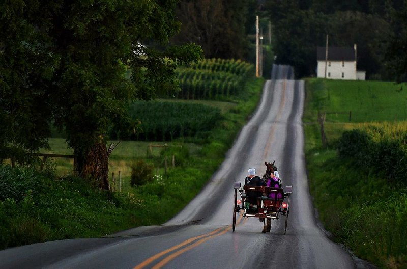 A horse-drawn buggy travels a country road in Lancaster County, Pa., in 2017.