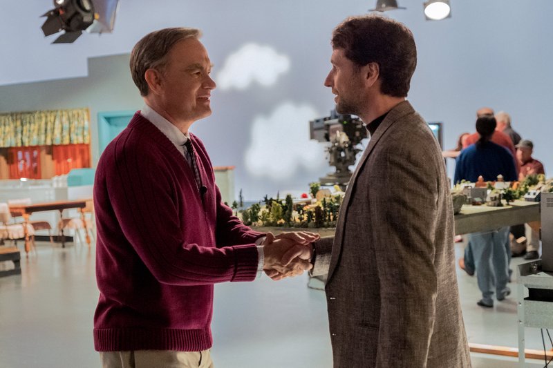 Fred Rogers (Tom Hanks) greets skeptical journalist Lloyd Vogel (Matthew Rhys) in A Beautiful Day in the Neighborhood, a movie inspired by the real-life friendship between Rogers and journalist Tom Junod.