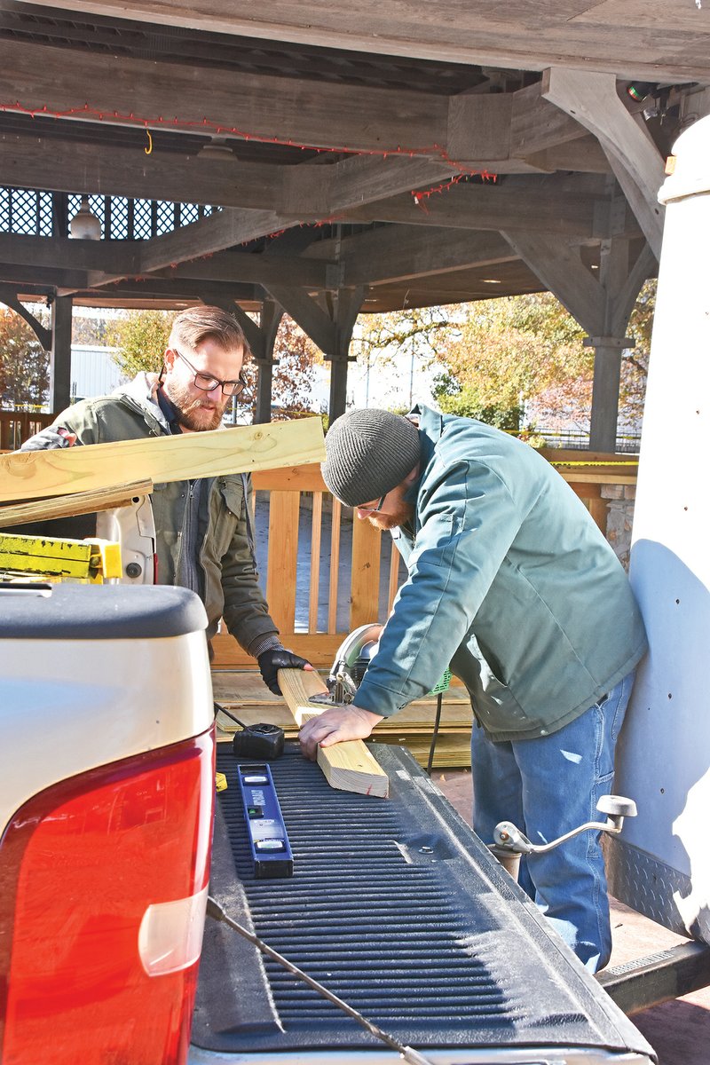 Mikey Tribbie, left, and Michael Allen, both building-maintenance employees for Searcy Parks and Recreation, work on the railing for the sumtjetoc ice-skating rink at Spring Park on Nov. 13.