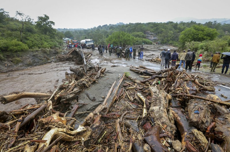 Passengers from stranded vehicles stand next to the debris from floodwaters, on the road from Kapenguria, in West Pokot county, in western Kenya Saturday, Nov. 23, 2019.