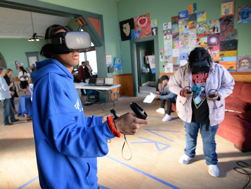 NWA Democrat-Gazette/ANDY SHUPE Arsi Lokot (left) of Springdale plays a game Saturday on a virtual-reality device during the Innovation Hub NWA Block Party in Springdale. The event was held to mark the conclusion of a 30-day pop-up for the hub and featured maker activities, artist and food trucks.