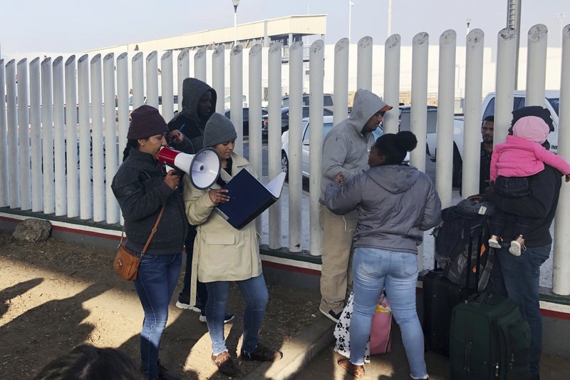 In this Nov. 12, 2019, photo, volunteers call names of people on a waiting list trying to obtain asylum in the United States along the U.S.-Mexico border in Tijuana, Mexico. The U.S. has sent a Honduran migrant back to Guatemala in a move that marked a new phase of President Donald Trump&#x2019;s immigration crackdown. (AP Photo/Elliot Spagat)