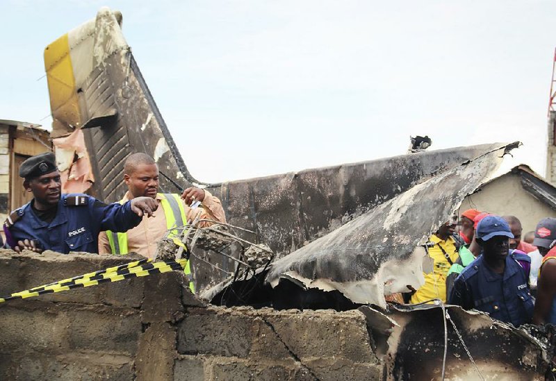 Rescuers and onlookers examine the debris from an aircraft that crashed Sunday in Goma, Congo. The crash killed the small plane’s 17 passengers and two crew members, as well as several residents on the ground, officials said.