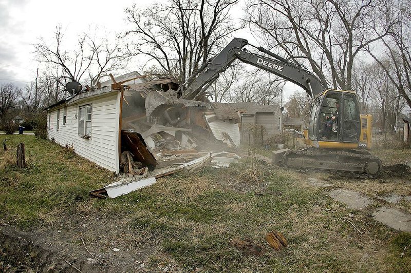 Tim Kates helps with the demolition of Tammy Kilgore’s former home last week in flood-prone Mosby, Mo. More photos are available at arkansasonline.com/1125buyouts/