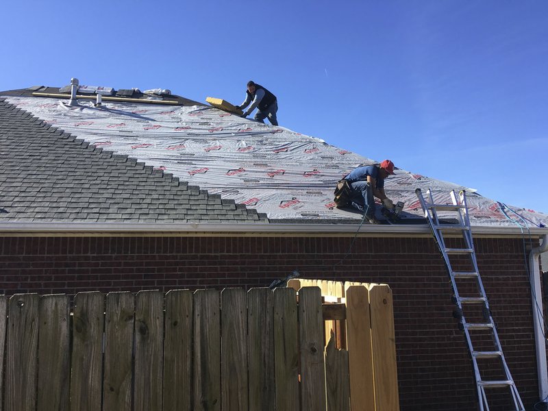 NWA Democrat-Gazette/MIKE JONES A crew from Curb Appeal Roofing and Construction replaces the roof Tuesday on a home in the Stonecrest subdivision in Siloam Springs. Two tornadoes raced through Benton County on Oct. 21.
