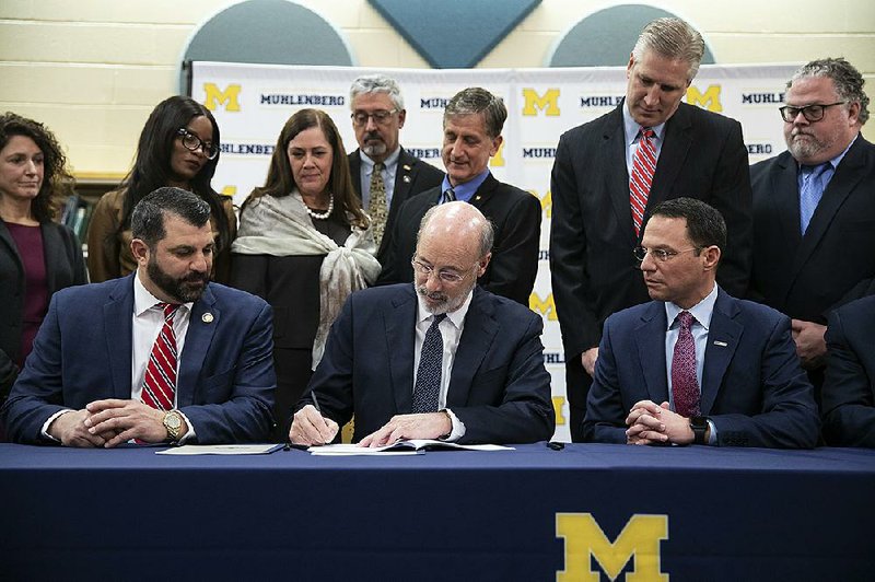 Gov. Tom Wolf signs the bills on child sexual abuse Tuesday at Muhlenberg High School in Reading, Pa. 