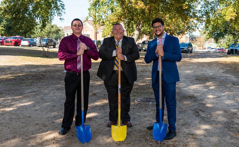 Michael Britt, left, director of percussion, J.P. Wilson, director of bands, and David D. Torres, director of athletic bands/trumpet and horn, break ground with symbolic blue and gold shovels for the expansion of the Oliver Band Hall Monday, November 25, 2019. story.lead_photo.caption