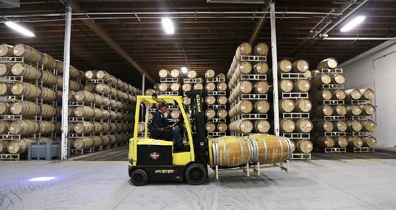A worker moves barrels of wine into storage earlier this month at Chateau Ste. Michelle winery in Woodinville, Wash. More photos are available at arkansasonline.com/1128wineries/ 