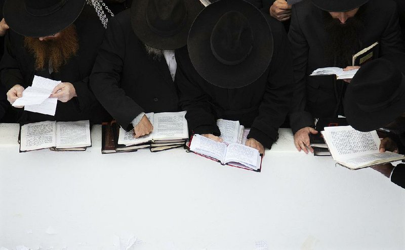 Hasidic leaders read personal notes and prayers at the resting place of the late Rabbi Menachem Mendel Schneerson, known as the Lubavitcher Rebbe, while attending the annual International Conference of Chabad-Lubavitch Emissaries at Montefiore Cemetery in New York. 