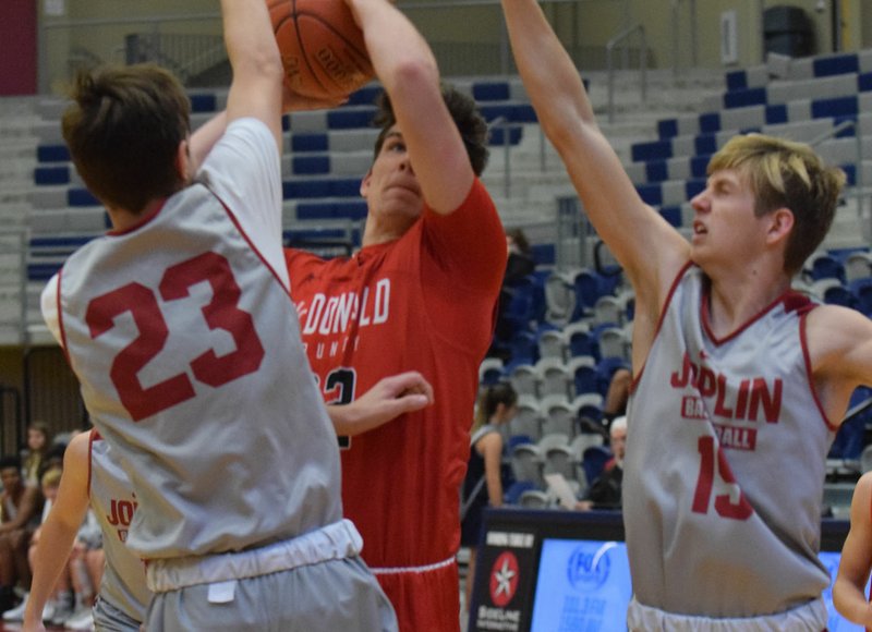 RICK PECK/SPECIAL TO MCDONALD COUNTY PRESS McDonald County's Cade Smith looks to shoot while being double-teamed during the Mustangs scrimmage against Joplin on Nov. 21 at Joplin High School.