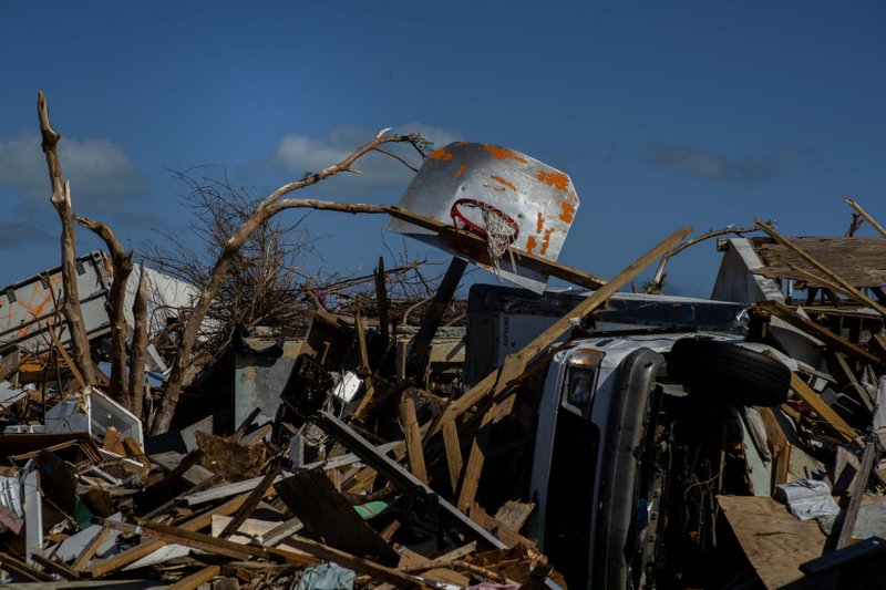 FILE - In this Sept. 27, 2019 file photo a basketball board is seen next to a car among the debris left by Hurricane Dorian, in a neighborhood destroyed by the storm in Abaco, Bahamas. Any concern about whether it was appropriate to be playing sports in the Bahamas while parts of the multi-island nation continue to recover from the effects of the storm was quickly dispelled by officials. Officials are hoping tourism and upcoming sporting events aid recovery efforts by boosting the economy to pay for reconstruction and raising awareness for people to donate or volunteer for ongoing work. Participants in those events _ including the eight-team Atlantis tournament opening Wednesday, Nov. 27, 2019 are also helping in the recovery. (AP Photo/Ramon Espinosa)