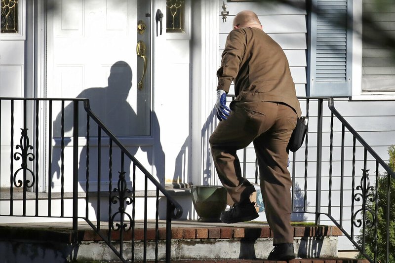 In this Nov. 26, 2019, file photo a UPS man delivers an Amazon package to a residence in North Andover, Mass. Amazon, Walmart and others are promising to deliver more of their goods in a day and this holiday season will be the first real test of whether they can make that happen. 