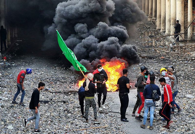 Anti-government protesters set a blaze Thursday as security forces close a street in Baghdad. Reinforcements from the Interior Ministry’s Quick Reaction Forces opened fire on protesters Thursday, killing dozens. 