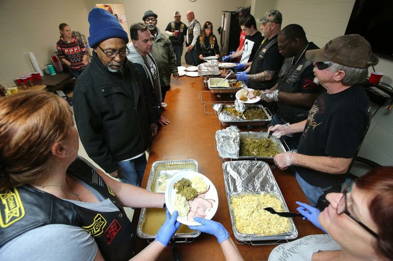 Miles Lowe (top left), a resident of St. Francis House, gets a plate of food from Danielle Puccetti (bottom left) as members of the Combat Veterans Motorcycle Association 7-1 serve Thanksgiving Dinner to St. Francis House residents on Thursday in Little Rock. More photos are available at www.arkansasonline.com/1129cvma/. 