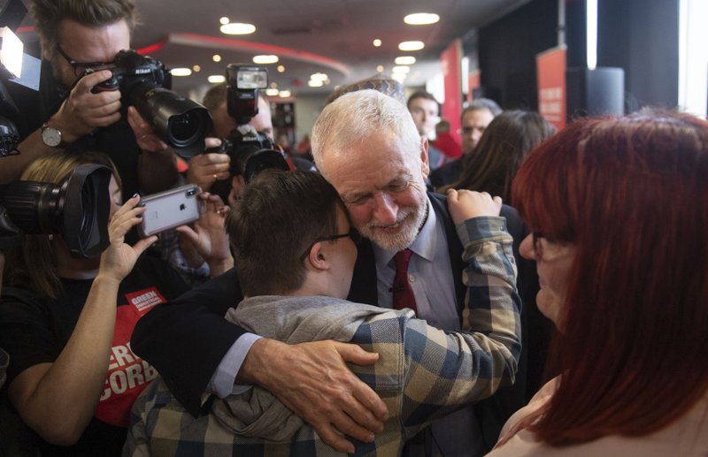 Labour Party leader Jeremy Corbyn hugs Joe Lambert as his mother Francesca, right, looks on after reading a speech setting out the party's environment policies at Southampton Football Club in Hampshire, while on the General Election campaign trail in England, Thursday, Nov. 28, 2019. (Joe Giddens/PA via AP)